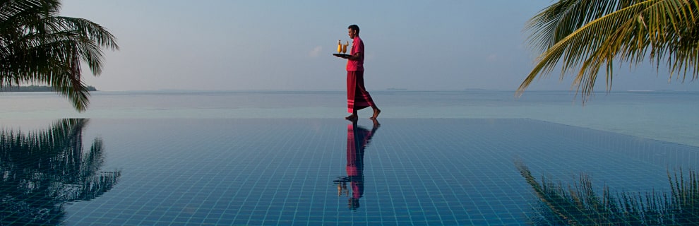 Infinity pool with three people looking out at the view