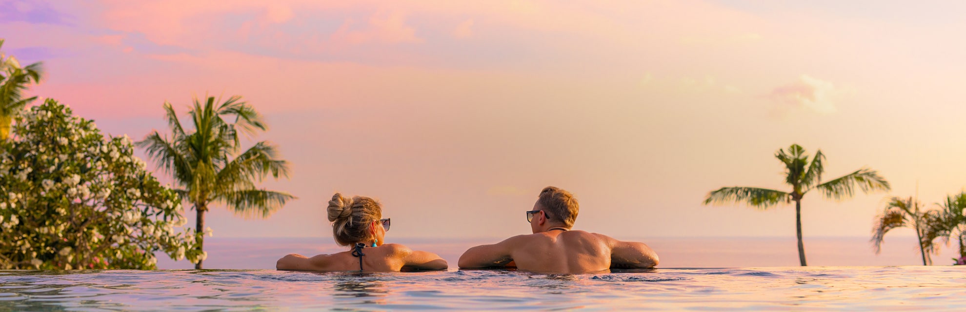 Infinity pool at sunset with 2 people looking out at the view